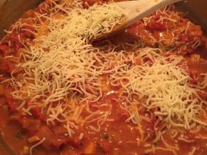 Adding shredded cheese to nine vegetable curry for toddlers
