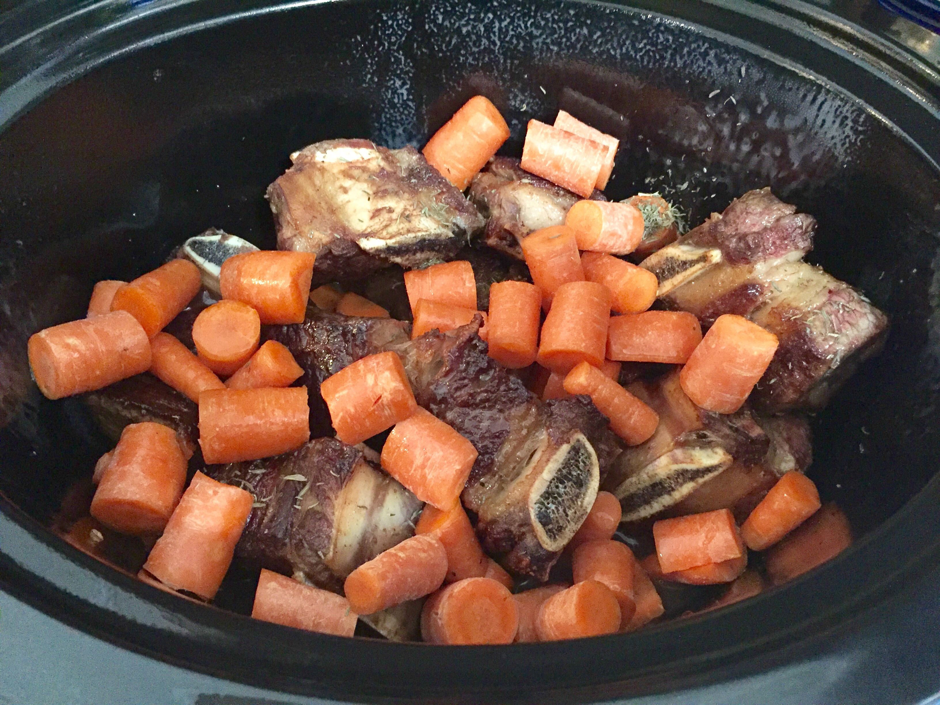 Adding carrots, thyme and stick to short ribs in slow cooker